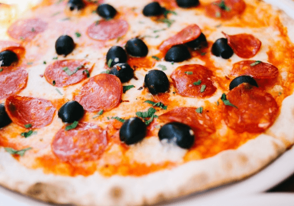 Pizza på grill med pepperoni og sorte oliven